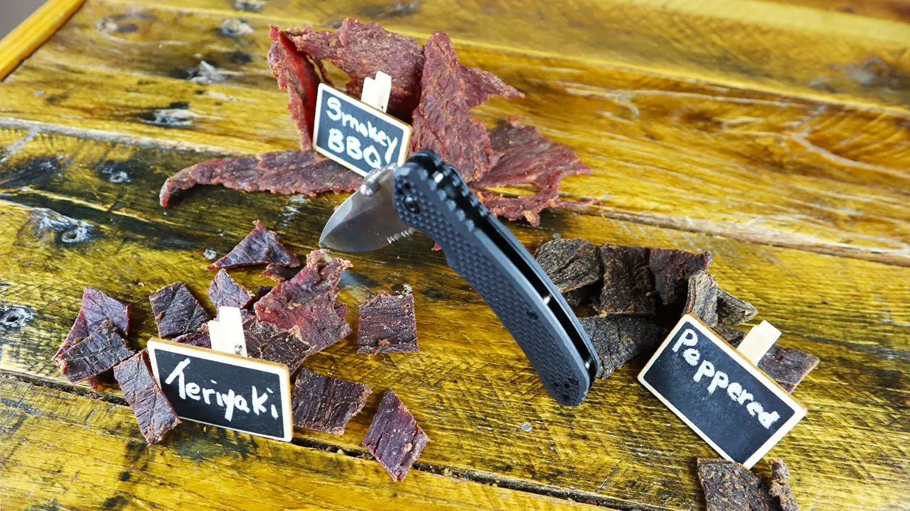 sliced of beef jerky on a wood background labeled with Knife